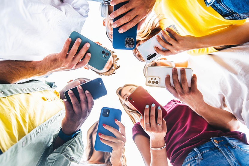 Teens in circle holding smart mobile phones 